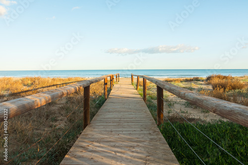 Beautiful wooden boardwalk leading to the beach. Perfect landscape photography with a dreamlike seascape horizon. POV postcard shot.