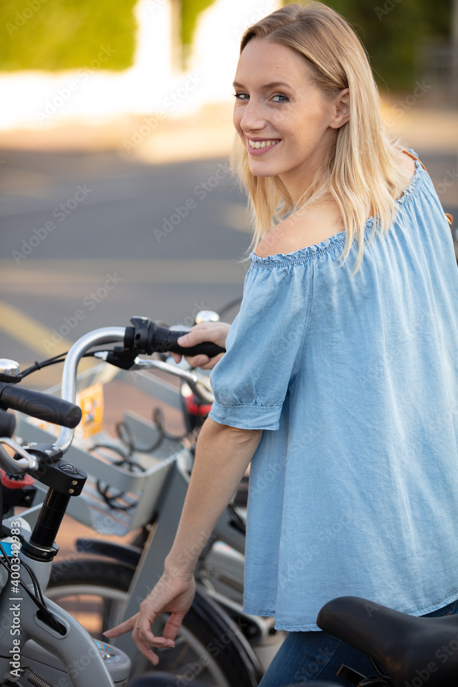 Fototapeta premium attractive girl unlocking rental bicycle