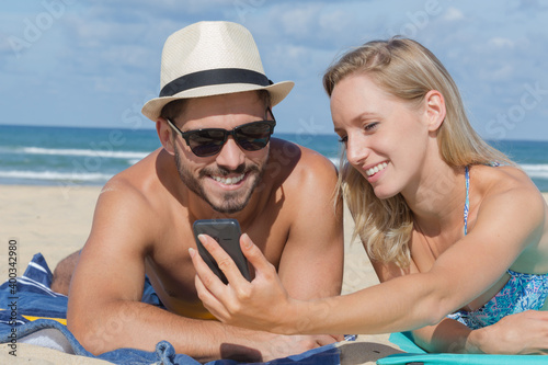 Fotografie happy couple looking at mobile phone on the beach