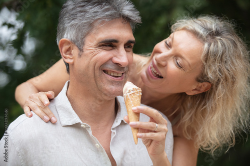 happy middle-aged couple looking at eachother while eating ice-cream