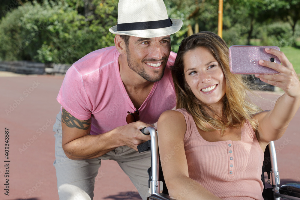 cheerful woman in wheelchair making a selfie with her boyfriend