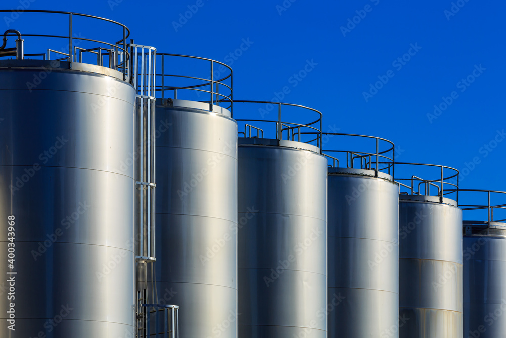 Industrial architecture. A row of giant metal tanks gleaming in the sunlight. Photographed at a dairy factory