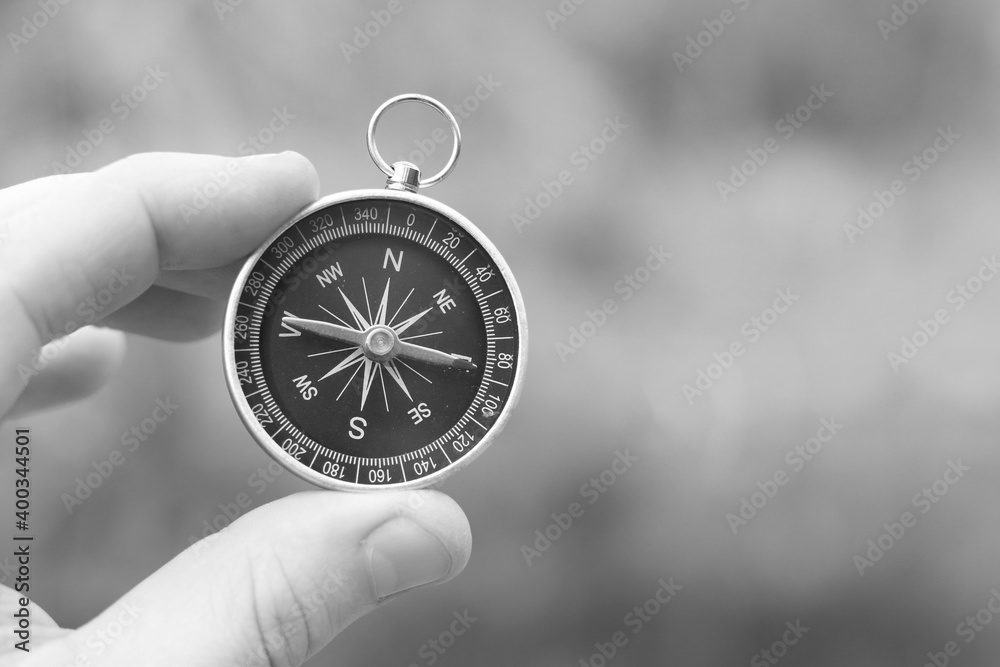 Old classic navigation compass and hand on natural background as symbol of tourism with compass, travel with compass and outdoor activities with compass Old classic navigation compass and hand on natural background as symbol of tourism with compass, travel with compass and outdoor activities with compass