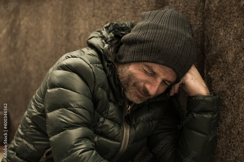Obraz premium dark and edgy urban portrait of middle aged sad and depressed unemployed man sitting outdoors on dirty street corner staircase feeling upset suffering depression problem