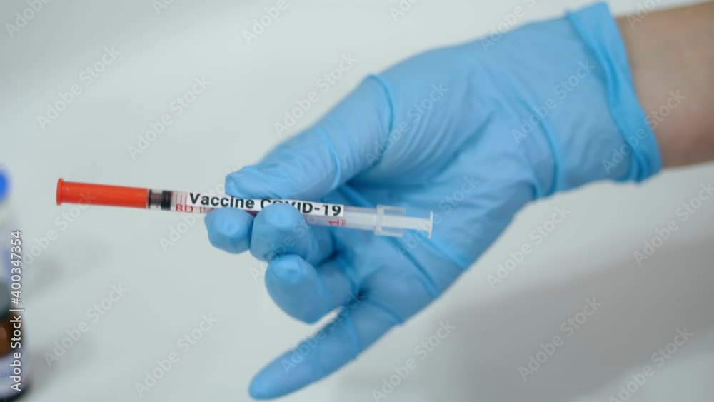 Coronavirus Vaccination. close-up. hands of a nurse or doctor, in blue medical gloves, hold a syringe with COVID-19 vaccine. new vaccine for prevention, immunization and treatment of coronavirus Coronavirus Vaccination. close-up. hands of a nurse or doctor, in blue medical gloves, hold a syringe with COVID-19 vaccine. new vaccine for prevention, immunization and treatment of coronavirus