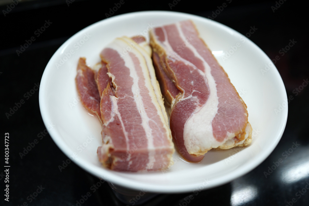 Slices of raw fresh pork belly cut on a white plate