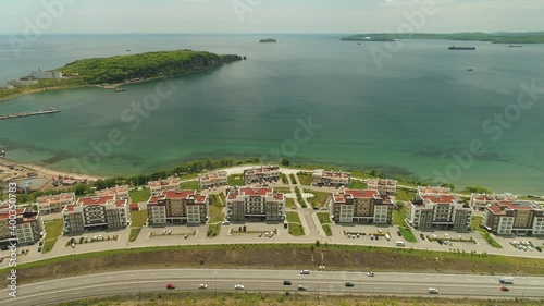 Aerial sideways modern district, blue sea, new road highway way traffic Vladivostok Russia epic cityscape from above. Residential complex development. Far East downtown nature. Summer. Horizon. Shot photo