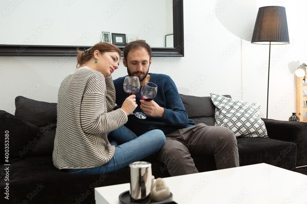 Young and happy couple drinking wine and relaxing at home