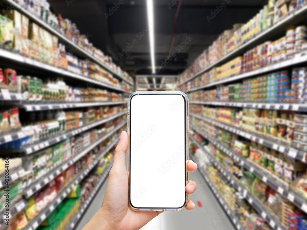 Woman holding blank white screen smartphone at supermarket with blur ...