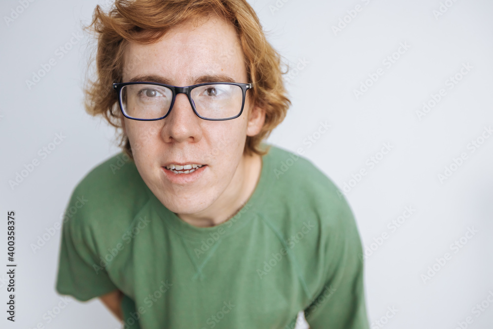 red-haired man in glasses and a green T-shirt looks at the camera and smiles on a white background red-haired man in glasses and a green T-shirt looks at the camera and smiles on a white background