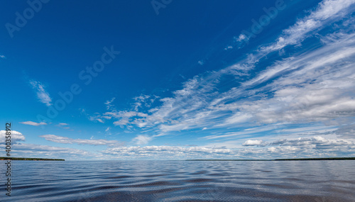 Panorama of calm lake, Kama river blue sky with clouds reflected in the water.