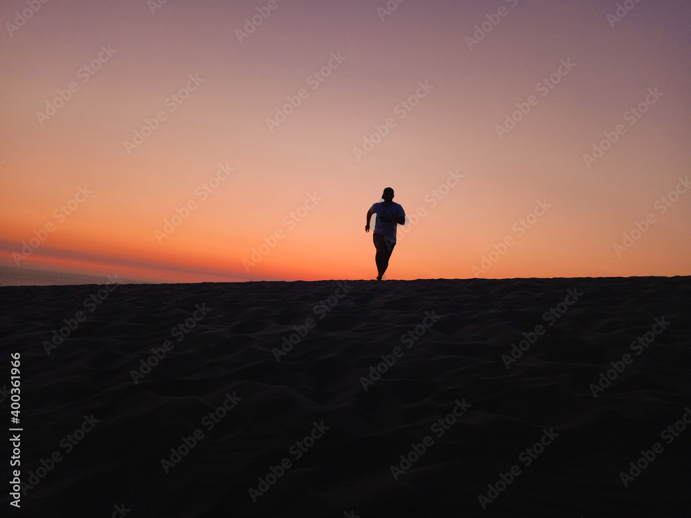the man run at sand dunes when sunset time.  