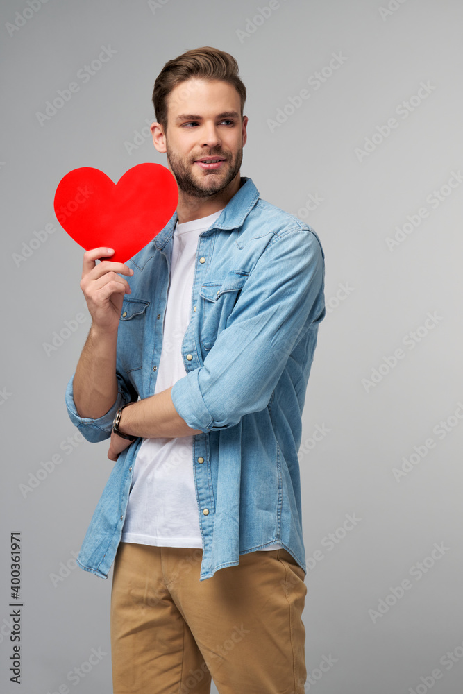 Portrait of charming man hold hand paper heart shaped card wear casual style shirt isolated over grey background Portrait of charming man hold hand paper heart shaped card wear casual style shirt isolated over grey background