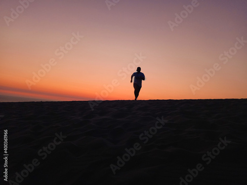 the man run at sand dunes when sunset time. 