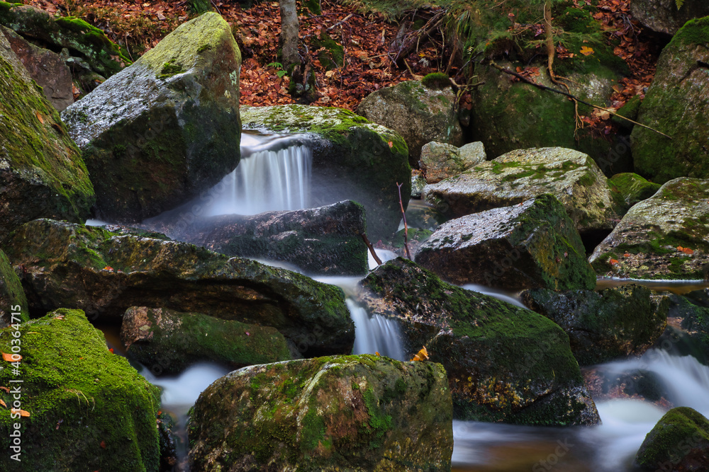 Autumn long exposure of creek Black (Big) Stolpich waterfalls in Jizera Mountain. Water falls into a deep forest canyon full of granite stones and rocks covered with green moss. Czech Republic Autumn long exposure of creek Black (Big) Stolpich waterfalls in Jizera Mountain. Water falls into a deep forest canyon full of granite stones and rocks covered with green moss. Czech Republic
