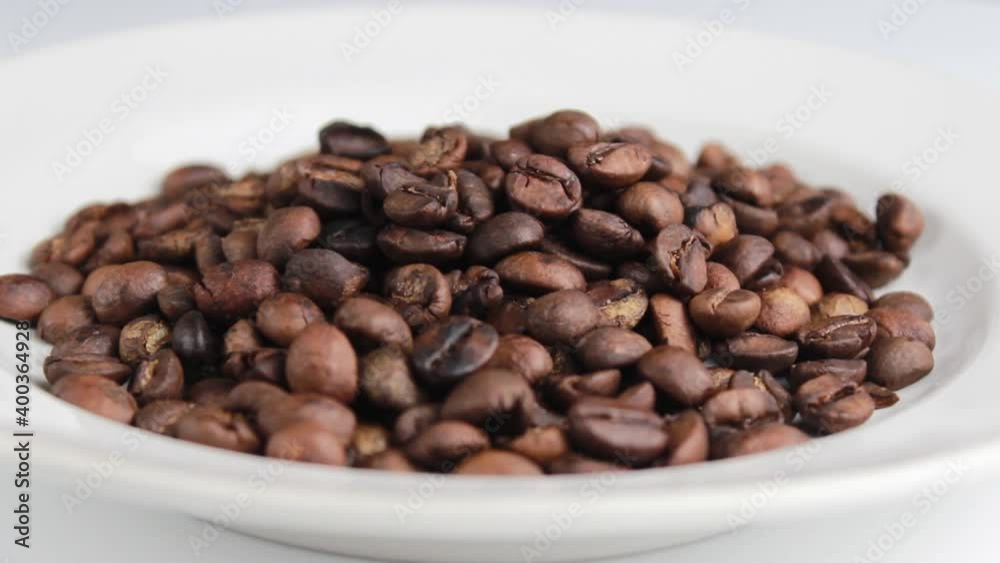 Roasted coffee beans in a white plate close-up. Selective shot. Roasted coffee beans in a white plate close-up. Selective shot.