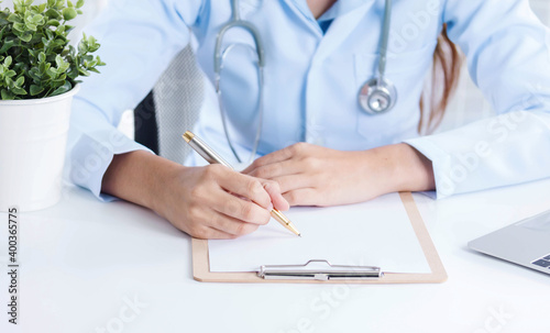 Doctor working withwriting on paperwork. Hospital background.