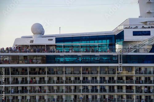 Detail close up view of superstructure with life boats and balcony cabins staterooms of modern Celebrity cruise ship or cruiseship liner against blue sky	 photo