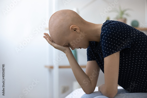 Desperate millennial female sick with cancer sit on bed unable to believe accept hard diagnosis. Depressed young woman oncology clinic patient feeling frustrated receiving bad test results. Copy space photo