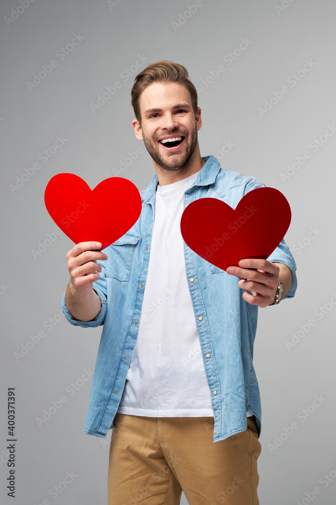 Portrait of charming man hold hand paper heart shaped card wear casual style shirt isolated over grey background Portrait of charming man hold hand paper heart shaped card wear casual style shirt isolated over grey background