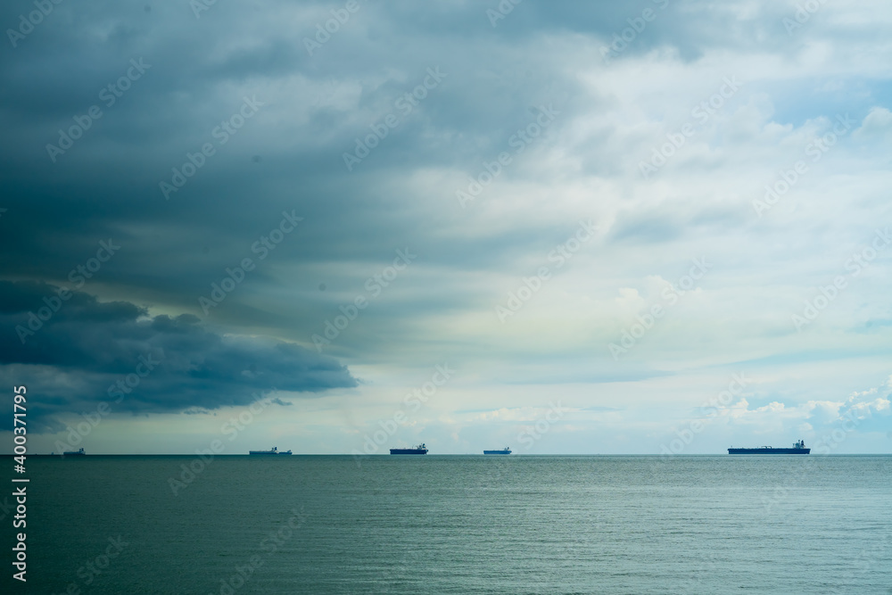 Seaview with ships in Port Dickson. Heavy clouds in the rainy season. The image contains soft focus, noise and grain.