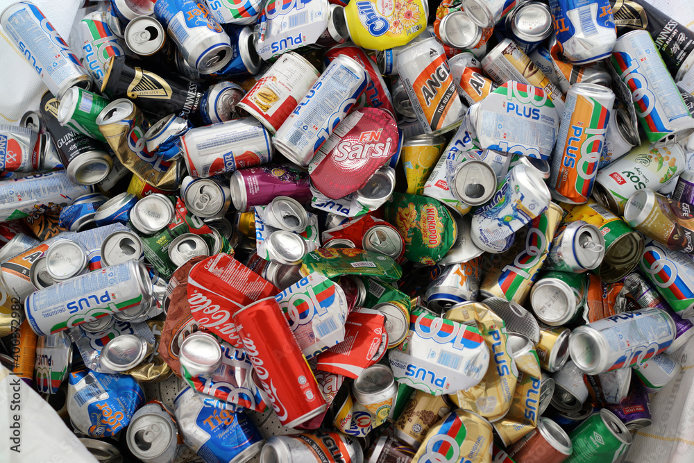 A heap of aluminum soda cans that are being stored for recycling in a recycling bin. All of the