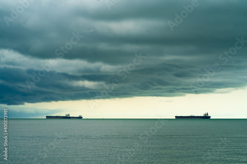 Seaview with ships in Port Dickson. Heavy clouds in the rainy season. The image contains soft focus, noise and grain. © ellinnur