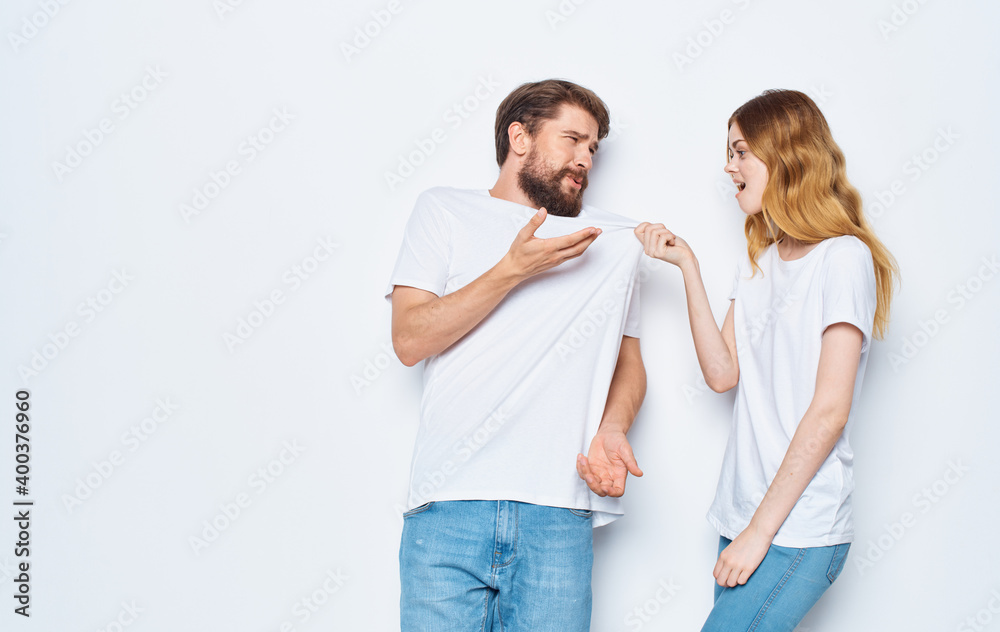 Man and woman in identical t-shirts on a light background jeans family fashion style Man and woman in identical t-shirts on a light background jeans family fashion style