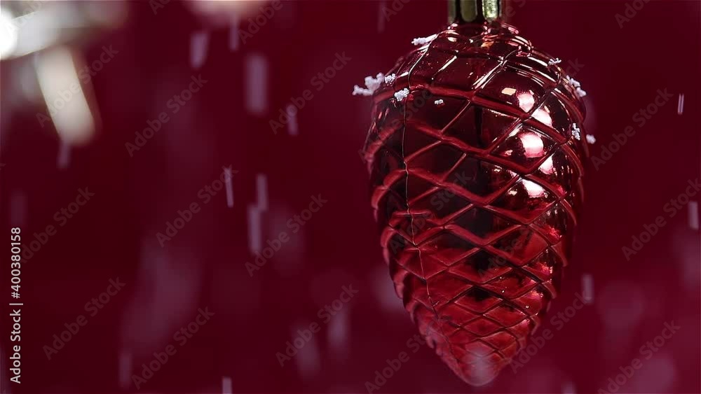 It snows on the red pinecone decor. Red New Year and Christmas background. 4K close-up. Slow motion. It snows on the red pinecone decor. Red New Year and Christmas background. 4K close-up. Slow motion.