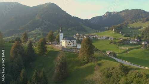 DRONE: Flying around a church and cemetery on top of a grassy hill overlooking the idyllic countryside in Soriska Planina. Aerial view of the idyllic Slovenian countryside on a sunny autumn evening. photo