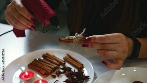 Close up of gluegun in action. Woman makes a Christmas decoration from cinnamon. photo