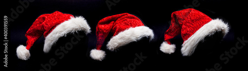 Drei Weihnachtsmützen vor schwarzem hintergrund