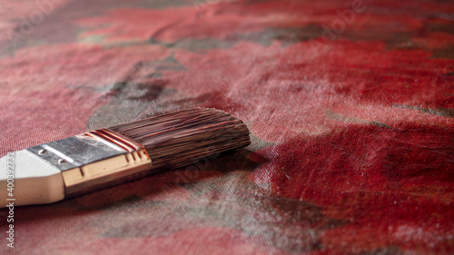 the brush lies on the canvas freshly painted with red paint