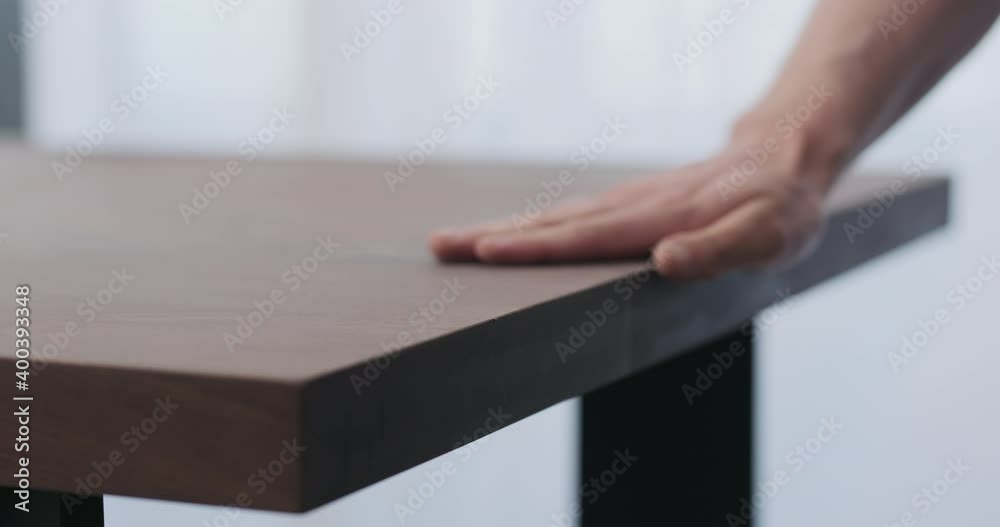 Slow motion of man hand checking toned walnut table surface before applying finish