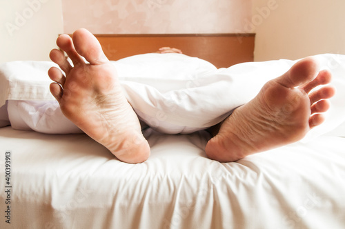 Feet of adult male sleeping in bed 