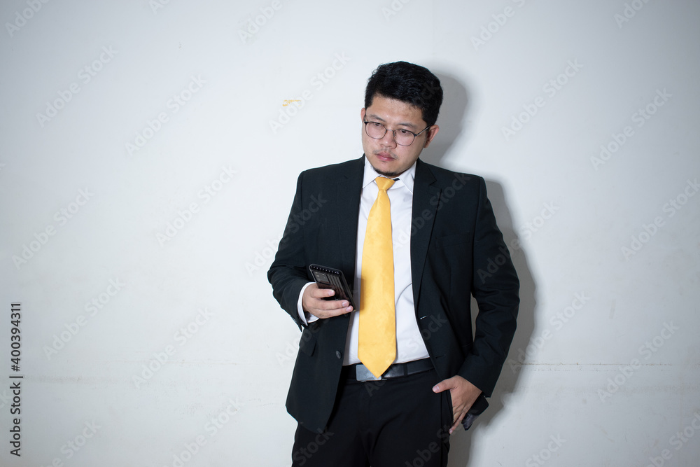 Portrait of a smiling businessman dressed in suit Yellow tie is working on mobile phone in white background. Portrait of a smiling businessman dressed in suit Yellow tie is working on mobile phone in white background.