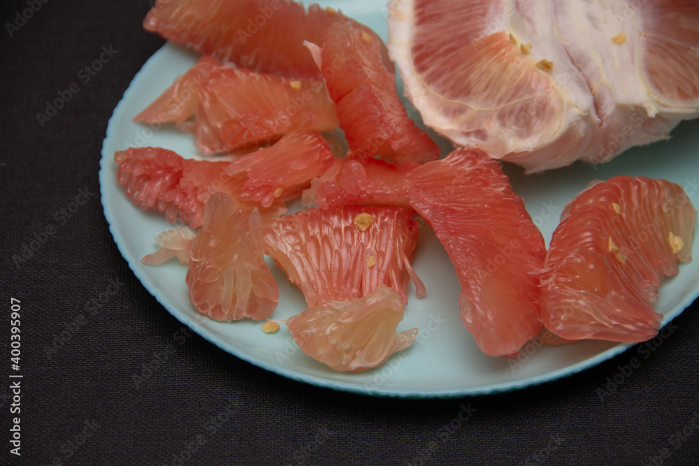 peeled slices of pink pomelo on a blue plate peeled slices of pink pomelo on a blue plate