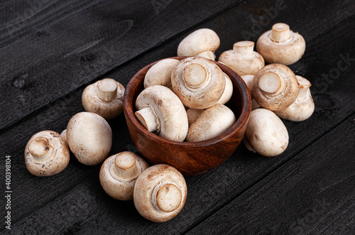 Champignons in wooden bowl on black background