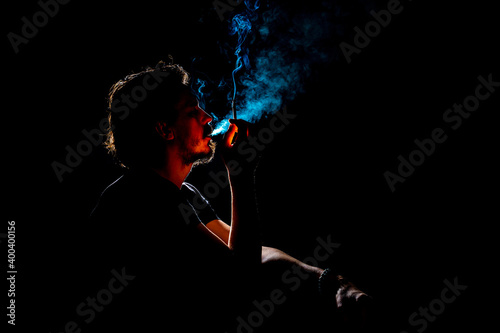 Colored silhouette of a smoking man on dark background.