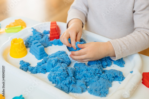Close view of child's hands playing with kinetic sand. Children's creative game for early development and fine motor skills.