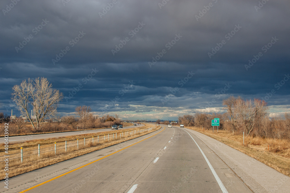 Beautiful dark blue sky over the highway. A landscape with a very unusual sky, trees without leaves and an asphalt road on an autumn day before a thunderstorm. Pacific Junction, IA, USA, 11-30-2019 Beautiful dark blue sky over the highway. A landscape with a very unusual sky, trees without leaves and an asphalt road on an autumn day before a thunderstorm. Pacific Junction, IA, USA, 11-30-2019