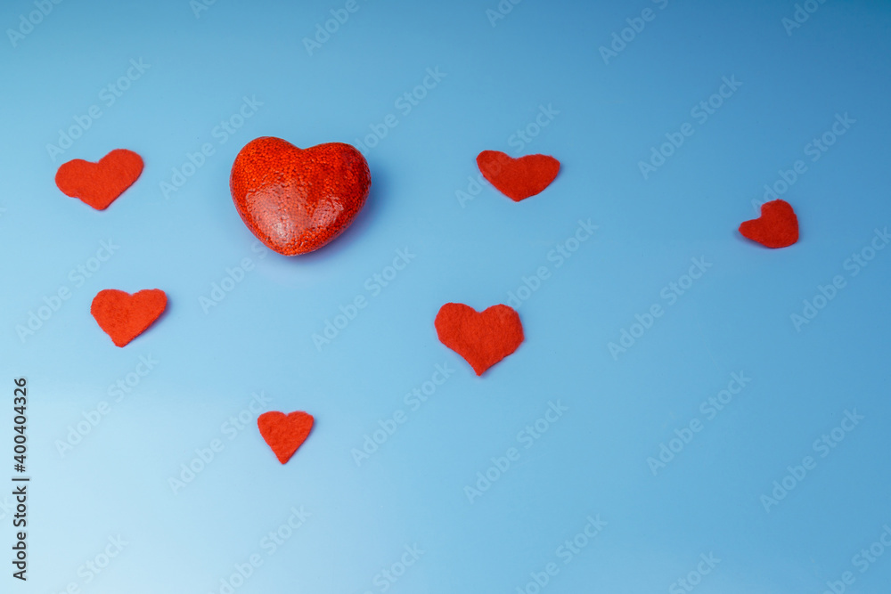 A large red heart and lying nearby hearts on a blue background.