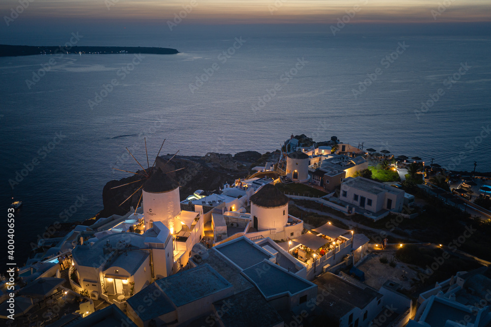 Fototapeta premium Oia town on Thira. Santorini island with colorful volcanic cliffs and deep blue sea aerial view