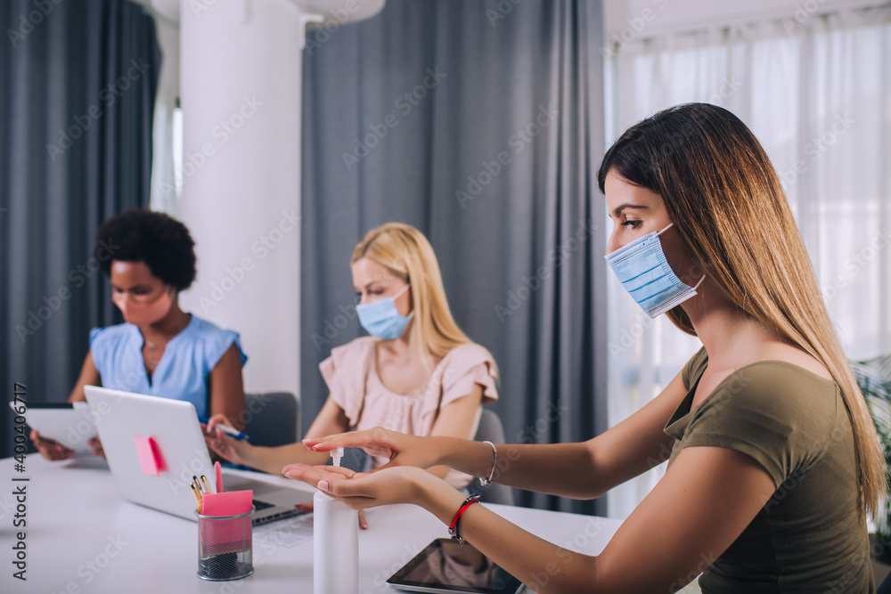 Fototapeta premium Female business colleagues with face masks working in the office