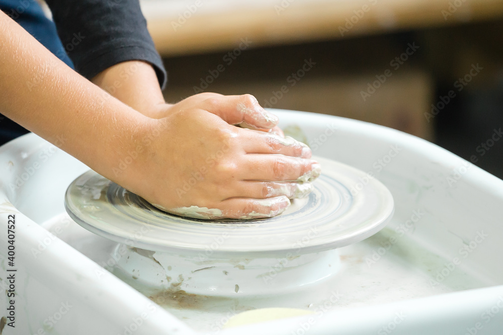 A boy sculpts a clay craft on a potter's wheel