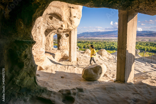 Female tourist walks around Uplistsikhe cave city exploring architectural structures photo