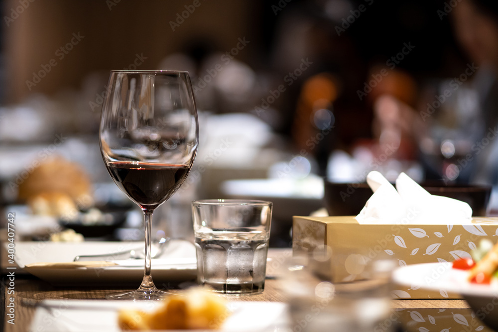 A glass of red wine is placed on the dining table in a fine dining restaurant
