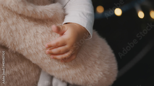 Close up baby little hand. Mother rocking her son near the christmas tree. High quality photo
