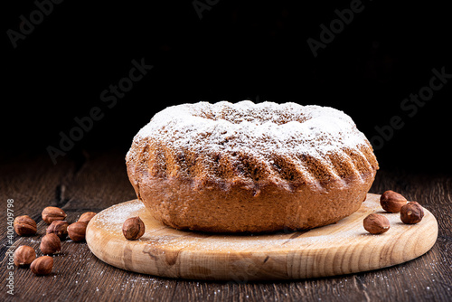 Round cupcake with hazelnuts on a cutting board.