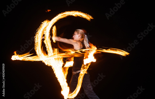 Sexy woman performer create beautiful fire patterns dark outdoors, beauty